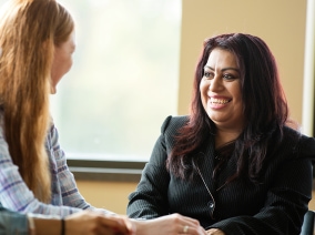 A volunteer assessor smiles while speaking with a student
