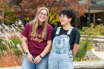 Two 金沙娱乐城 students laughing together outside on campus